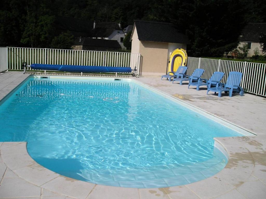 a swimming pool with blue chairs and a playground at Gîte de France Les saulières pour 2 2 épis - Gîte de France 2 personnes MAE-1333 in Monceaux-sur-Dordogne