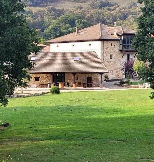 a large house with a green field in front of it at La cabaña de San Pelayo in San Pelayo