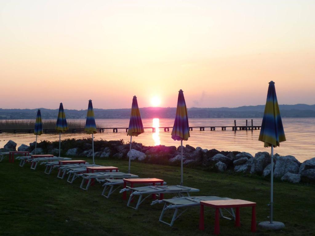 a row of tables and umbrellas with the sunset at B&B Topaze in Sirmione