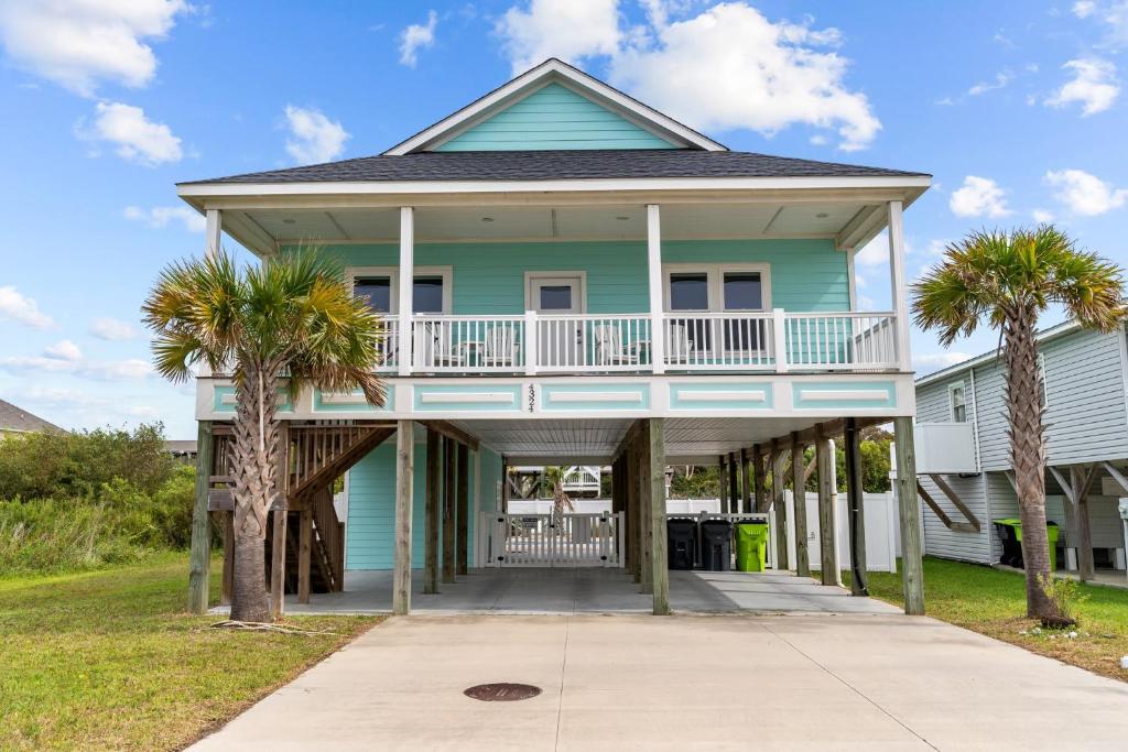 una casa con palmeras delante en Beachside Charm Pool Spa & 3-Min Walk to Shore, en Oak Island