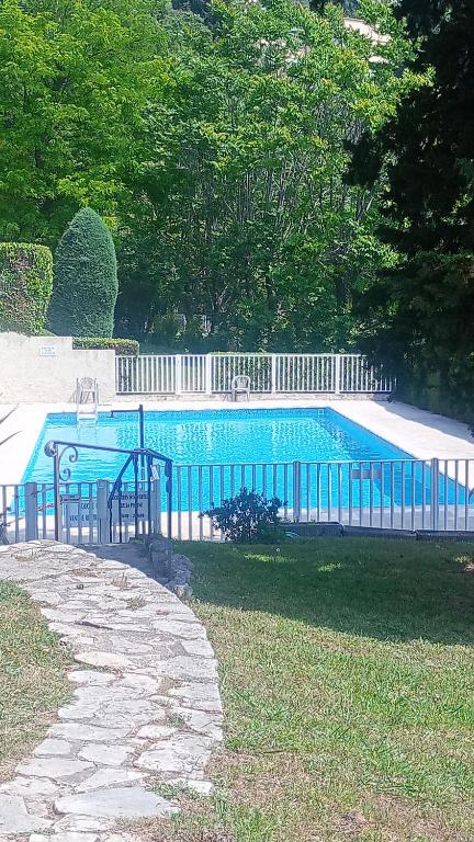 une piscine bleue entourée d'une clôture blanche. dans l'établissement 3 pièces avec piscine et jardin, à Grasse