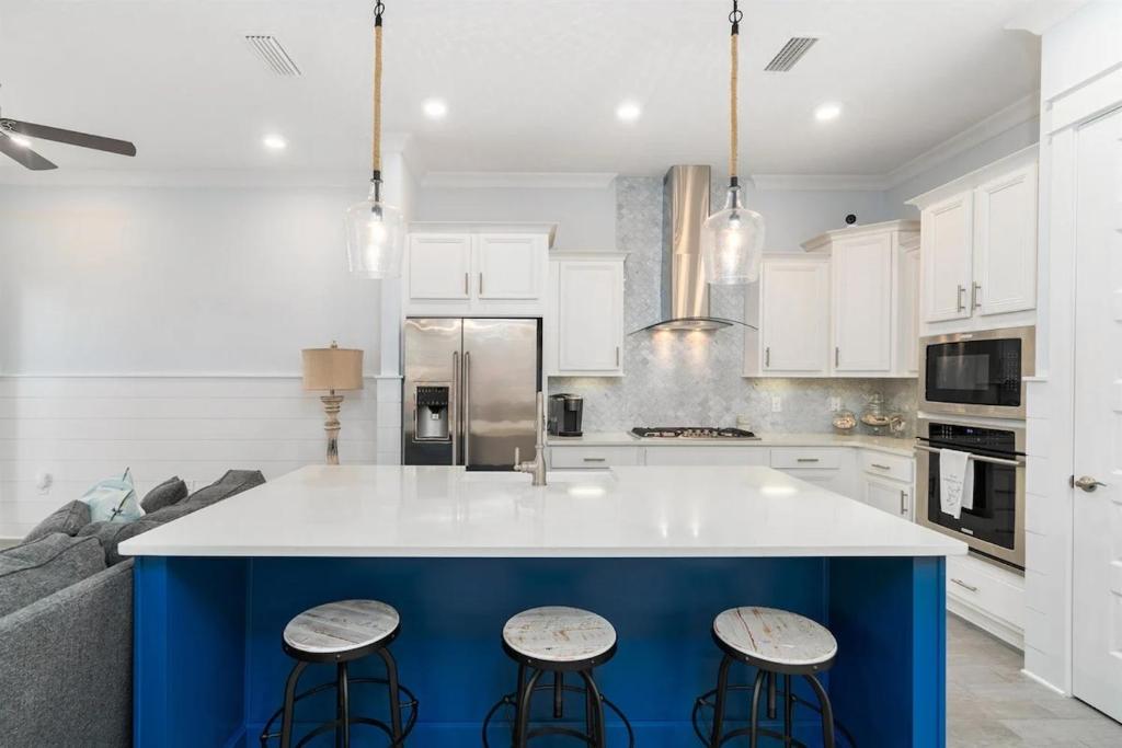 a kitchen with a blue island with two stools at Isle be 'SEA'ing You in Inlet Beach