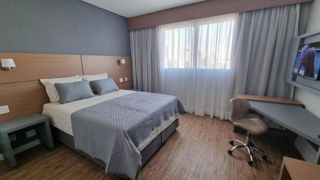 a hotel room with a bed and a television at Apartamento Santos praia Helbor Stay in Santos