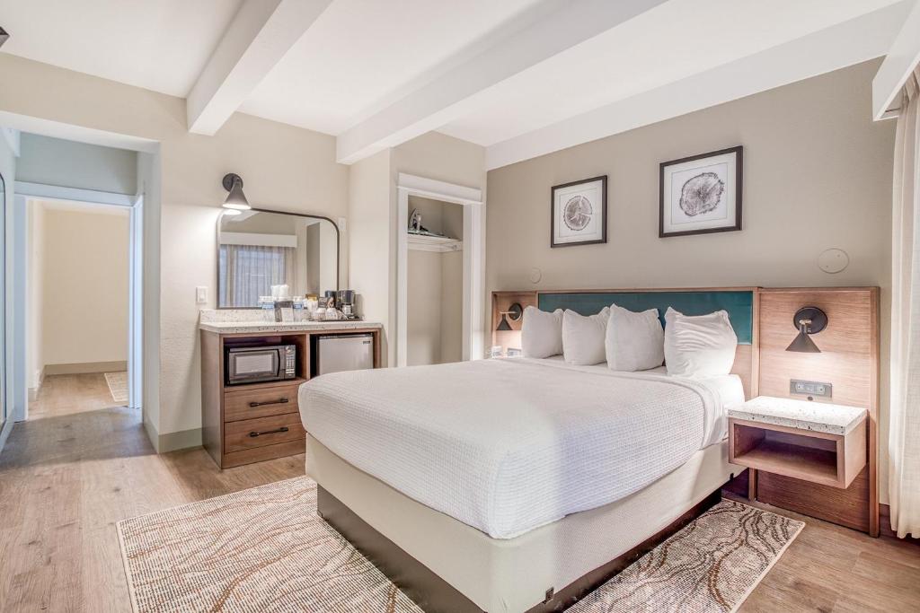 リンカーンシティにあるBeachfront Manor Hotelの大きな白いベッドと鏡のある寝室