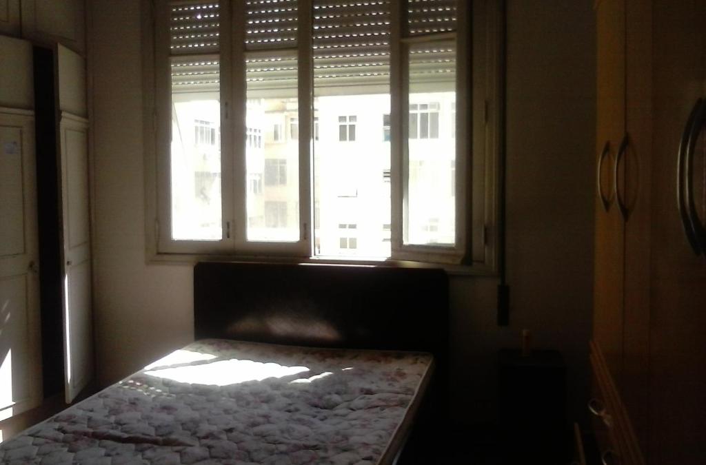 Cama en habitación con 2 ventanas en Apartamento Nossa Senhora, en Río de Janeiro