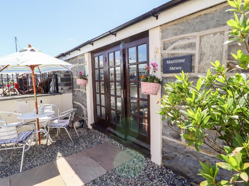 a patio with a table and chairs and an umbrella at Maritime Mews, 6 The Oakleys in Porthmadog