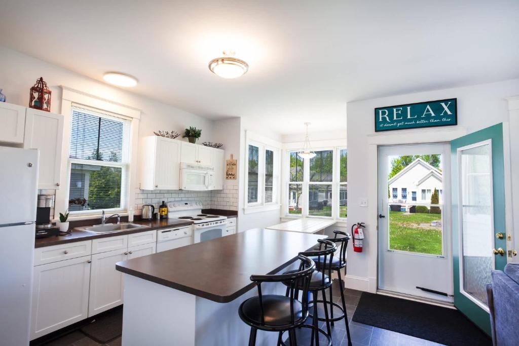 a kitchen with white cabinets and a kitchen island with stools at The Milkweed - 18 Meadow View in Cherry Valley