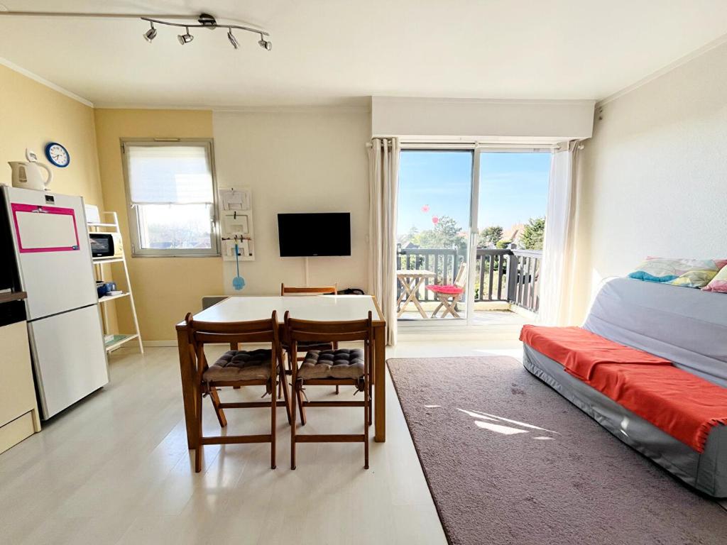 une chambre avec une table et un réfrigérateur et un lit dans l'établissement T2 Logement entier, balcon, piscine, tennis et accès direct à la plage!, à Cabourg