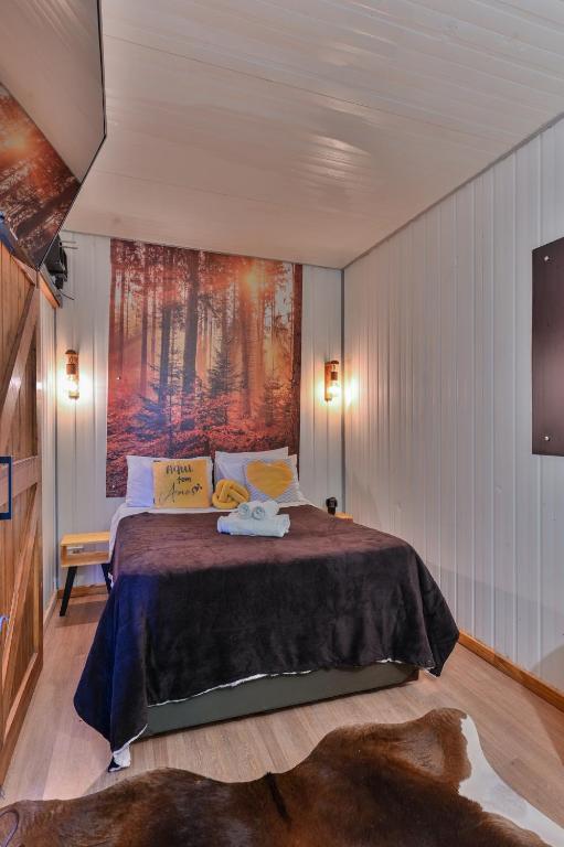 a bedroom with a bed with a painting on the wall at Recanto Lira 2 in Monte Verde