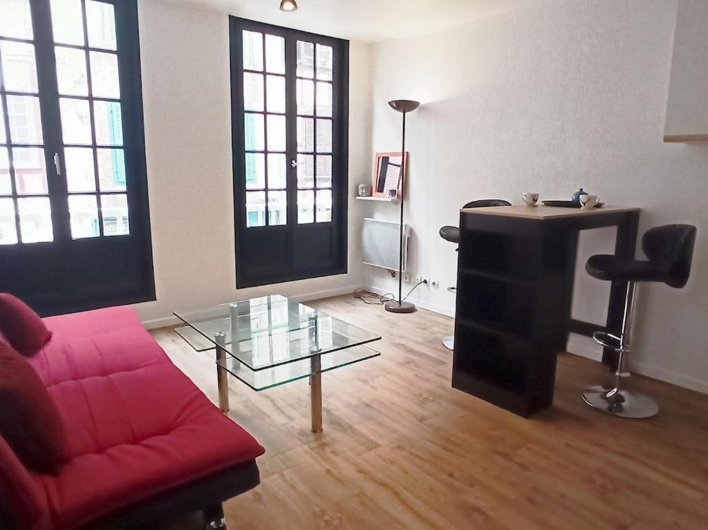 un salon avec un canapé rouge et une table en verre dans l'établissement Appartement deux pièces 2-4 personnes centre de Bayonne quartier dynamique et pieton, à Bayonne