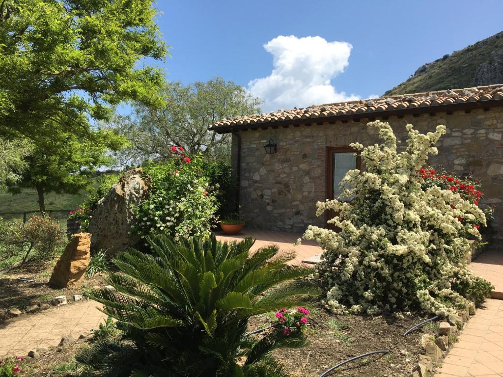 a garden in front of a stone house with flowers at La Casa del Monte d'Oro in Collesano