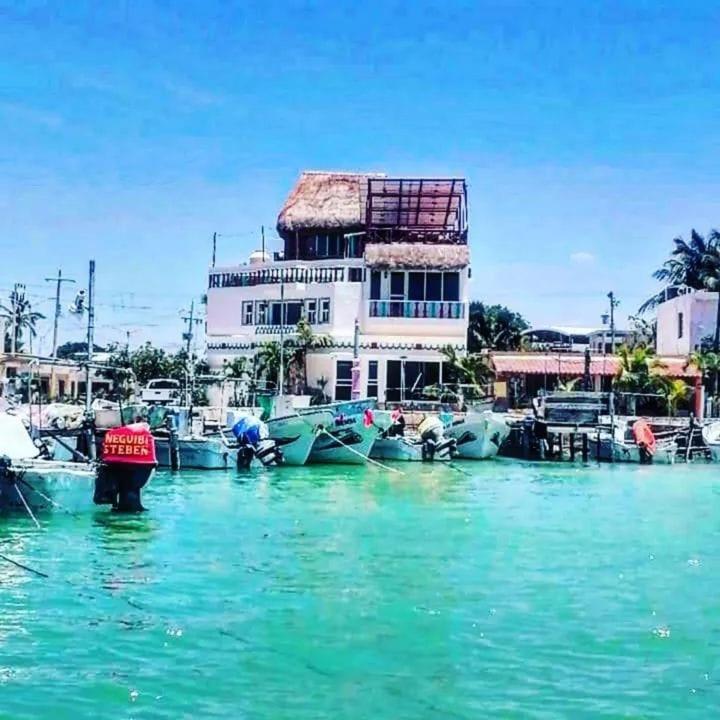 a building on the water with boats in the water at Hotel y Restaurante Macumba in Río Lagartos