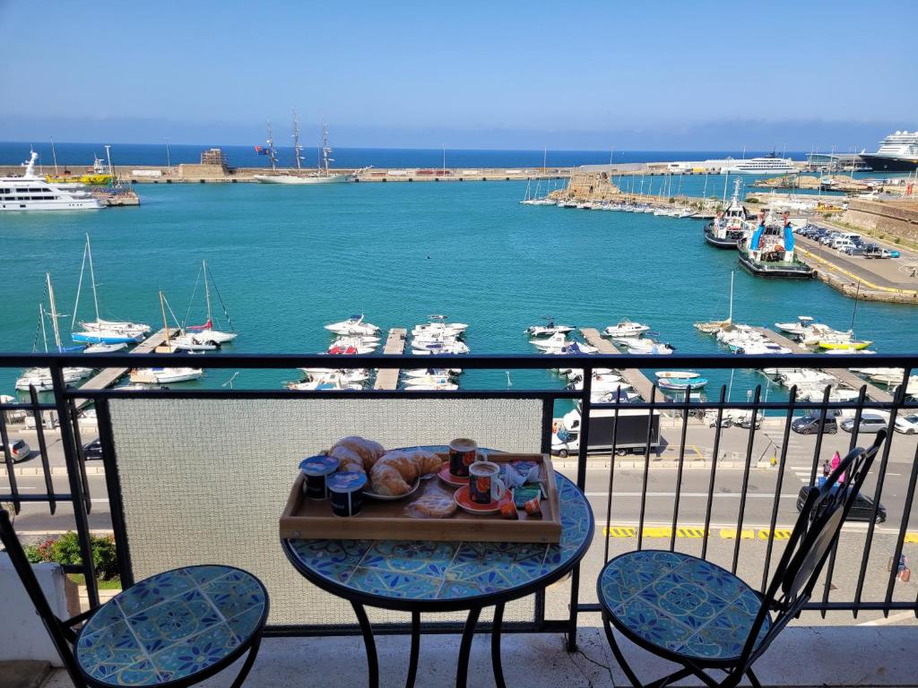 Una bandeja de comida en una mesa en un balcón con un puerto. en House Angelina, en Civitavecchia