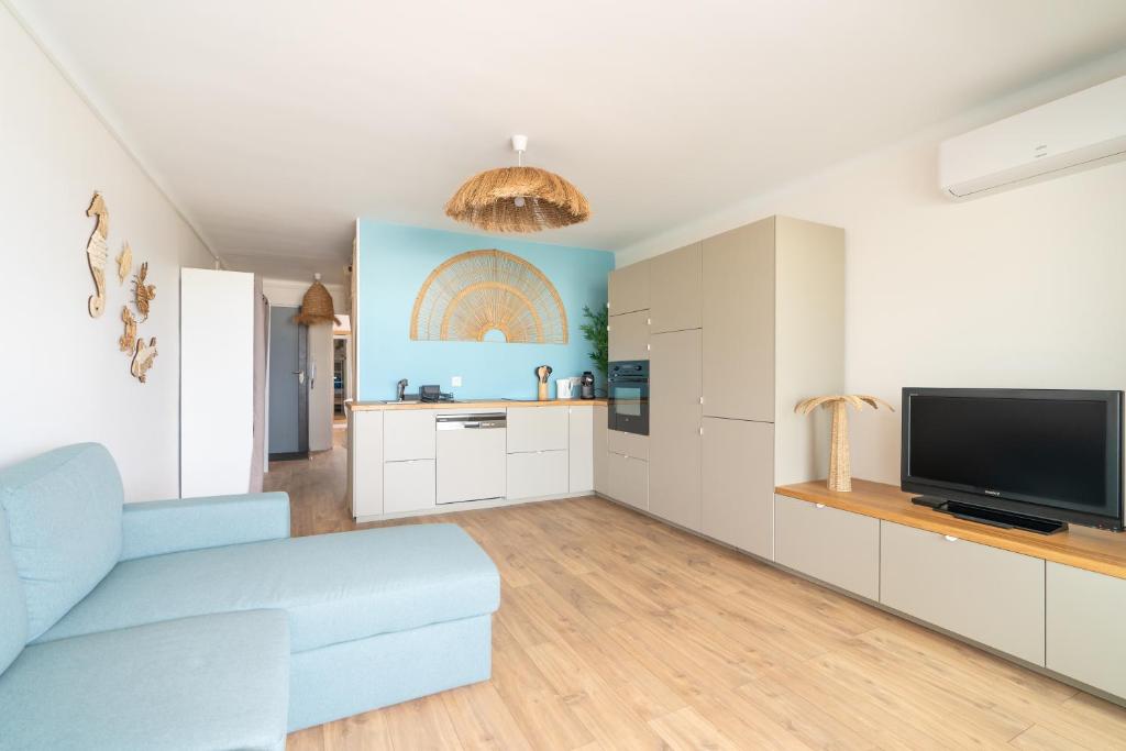 un salon avec un canapé bleu et une télévision dans l'établissement Bleu Camargue, au Grau-du-Roi