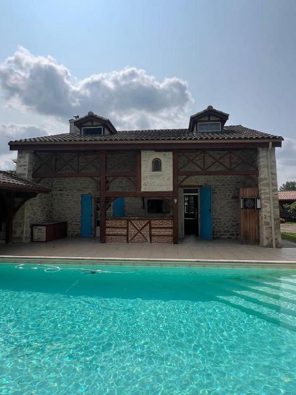 une maison avec une piscine d'eau en face de celle-ci dans l'établissement Maison sur Lot, à Villeneuve-sur-Lot