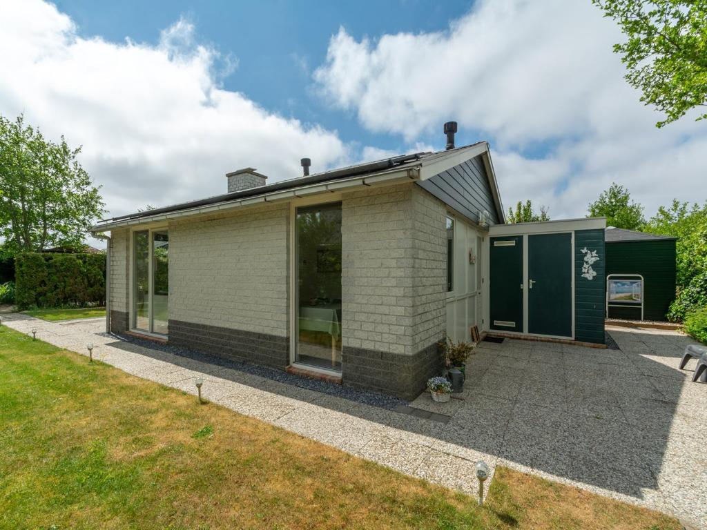 una pequeña casa blanca con un garaje verde en Holiday Home near Petten Beach with Pool, en Petten