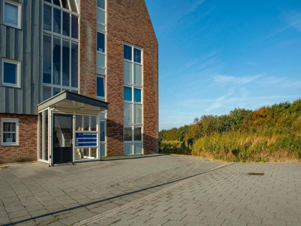 a large brick building with a blue sign in the doorway at Penthouse Duinerei by the sea with sauna in Callantsoog