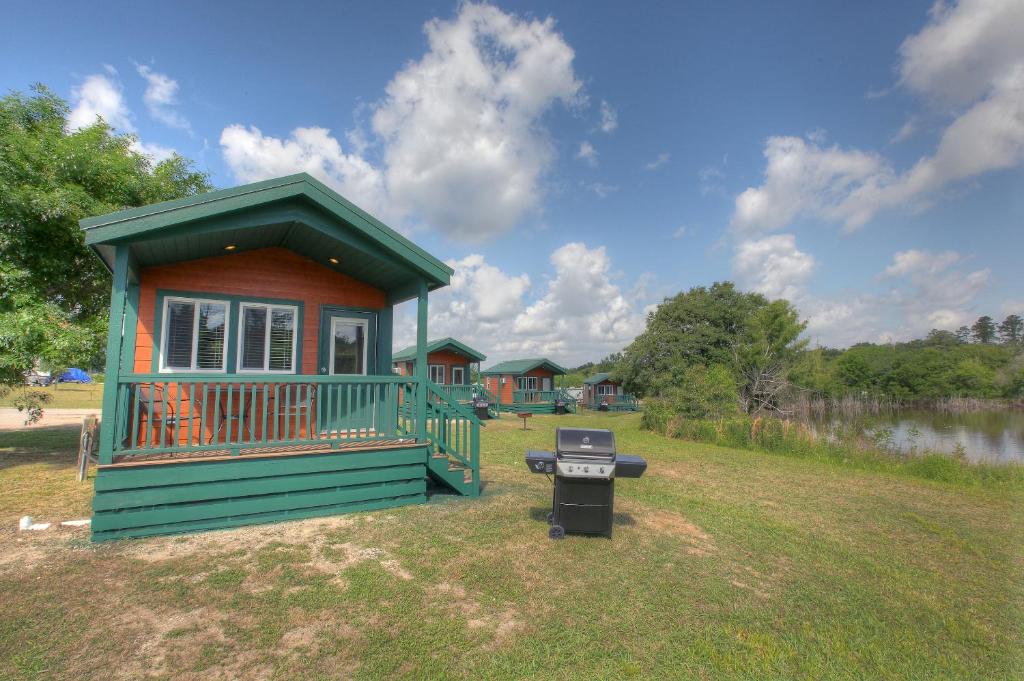 a small house with a grill in a yard at Lake Conroe Queen Studio Cabin 5 in Willis