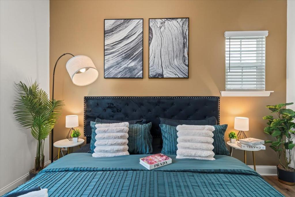 une chambre avec un lit bleu avec trois tableaux sur le mur dans l'établissement Luxe King 3BR Townhouse Mins to Uptown Charlotte!, à Charlotte