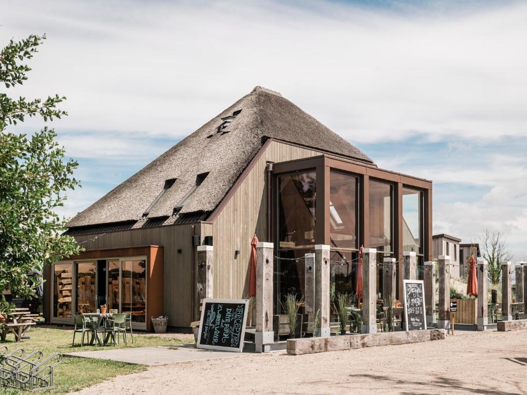 een klein gebouw met een rieten dak bij Charming Woodlodge Stay in Callantsoog