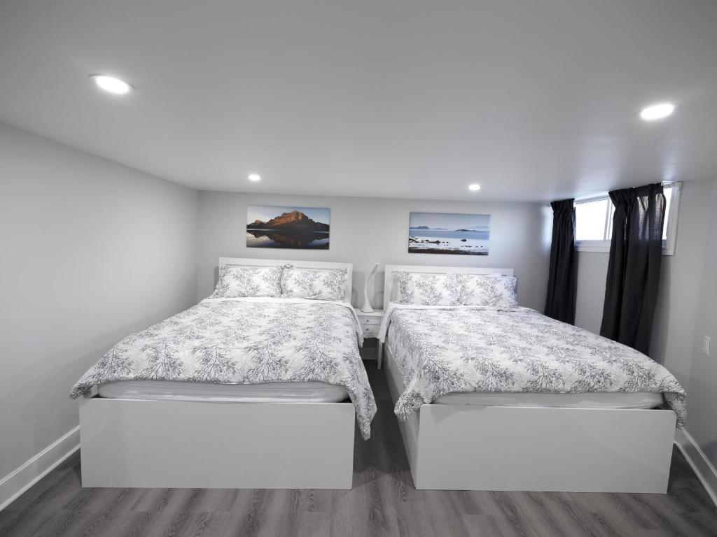 two beds in a bedroom with white walls at Serene Niagara Inn in Niagara Falls