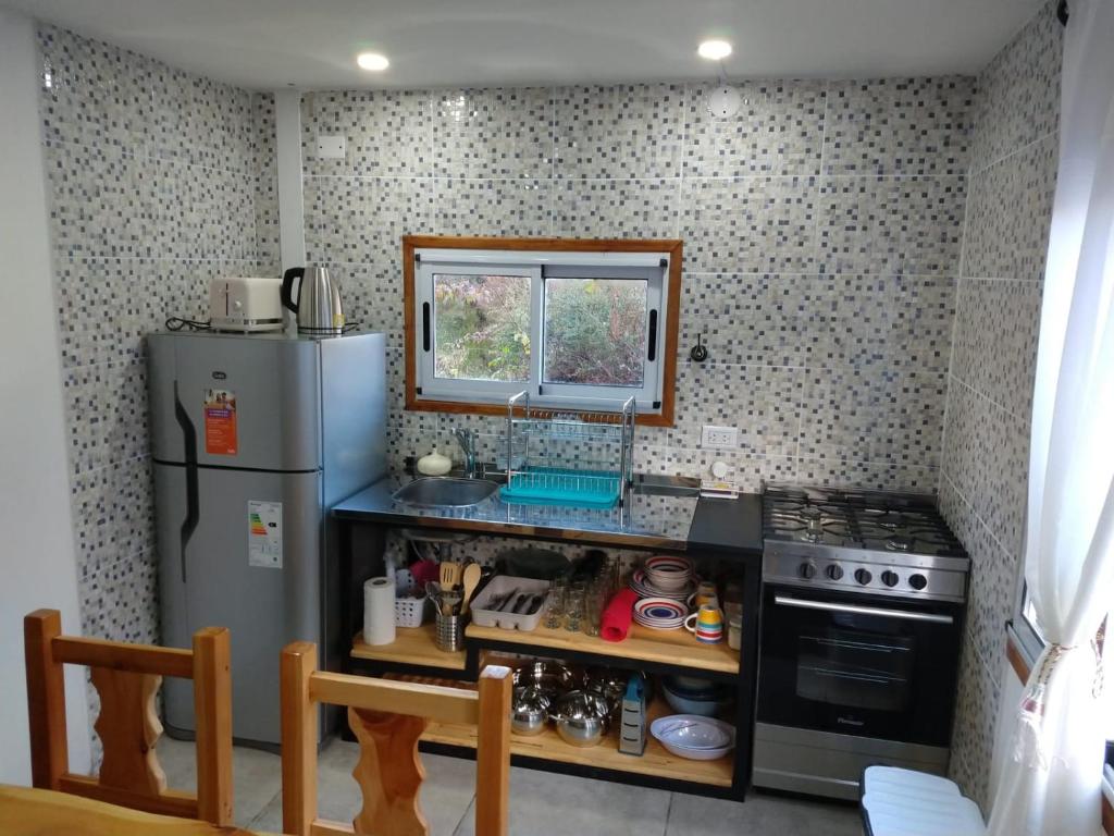 a small kitchen with a refrigerator and a window at La Loisa - Bungalows & Rooms in San Carlos de Bariloche