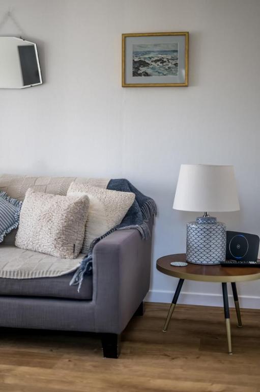 a living room with a couch and a table with a lamp at Kewwater Getaways Seafront Apartment in Johnshaven in Johnshaven