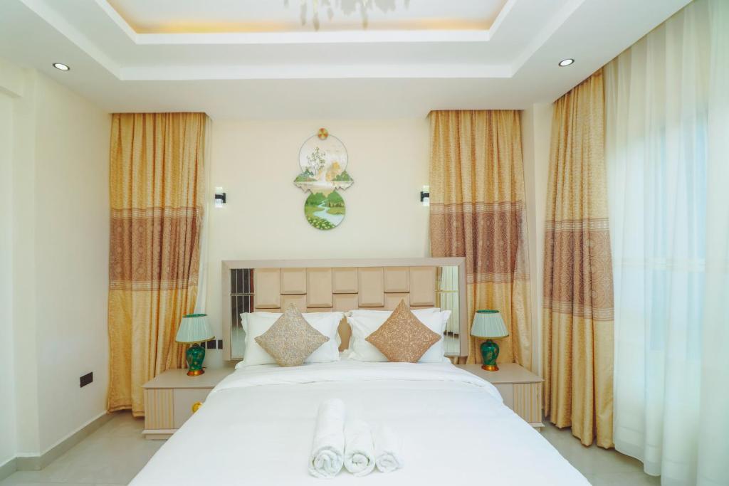 a bedroom with a large white bed with two lamps at Mira Heights in Mombasa