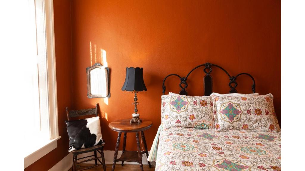 een slaapkamer met een bed en een tafel met een lamp bij Zane Grey - Historic Hotel in Cimarron