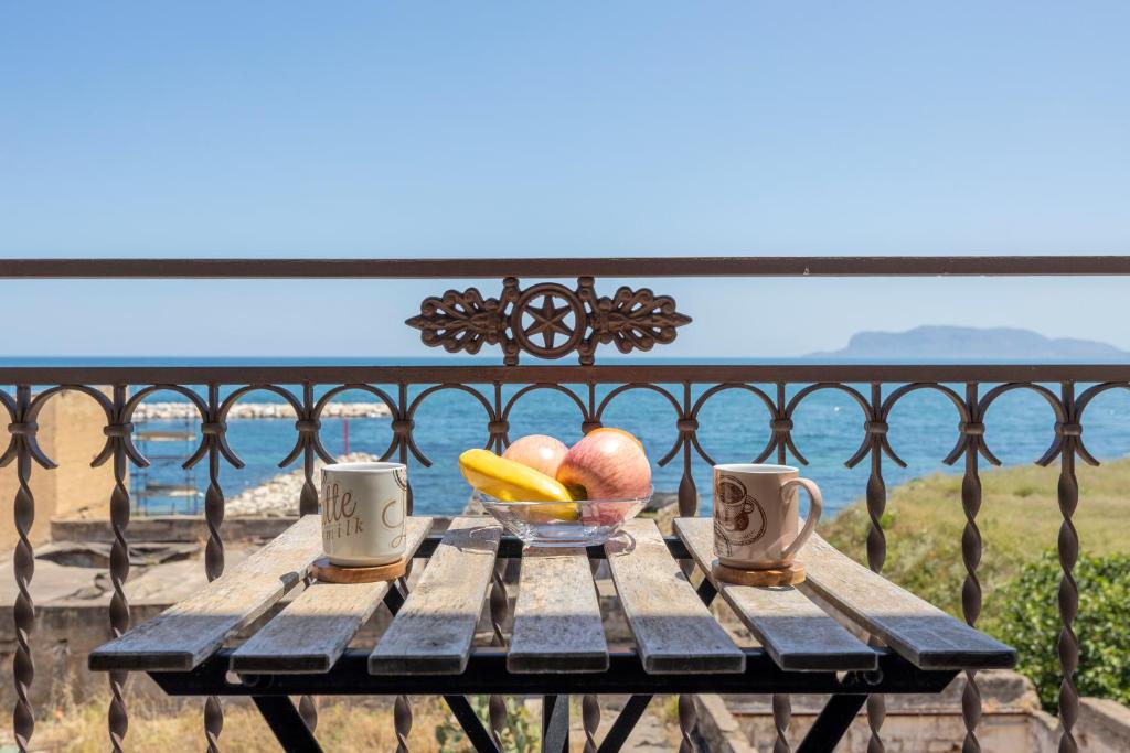 a wooden table with a bowl of fruit and two mugs at Sant'Erasmo luxury home in Palermo