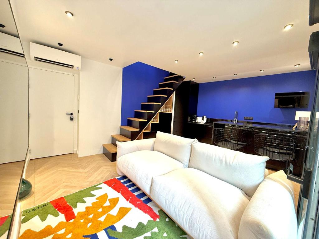 Una sala de estar con un sofá blanco y una escalera. en Sur les traces de Cyrano Duplex, en Bergerac