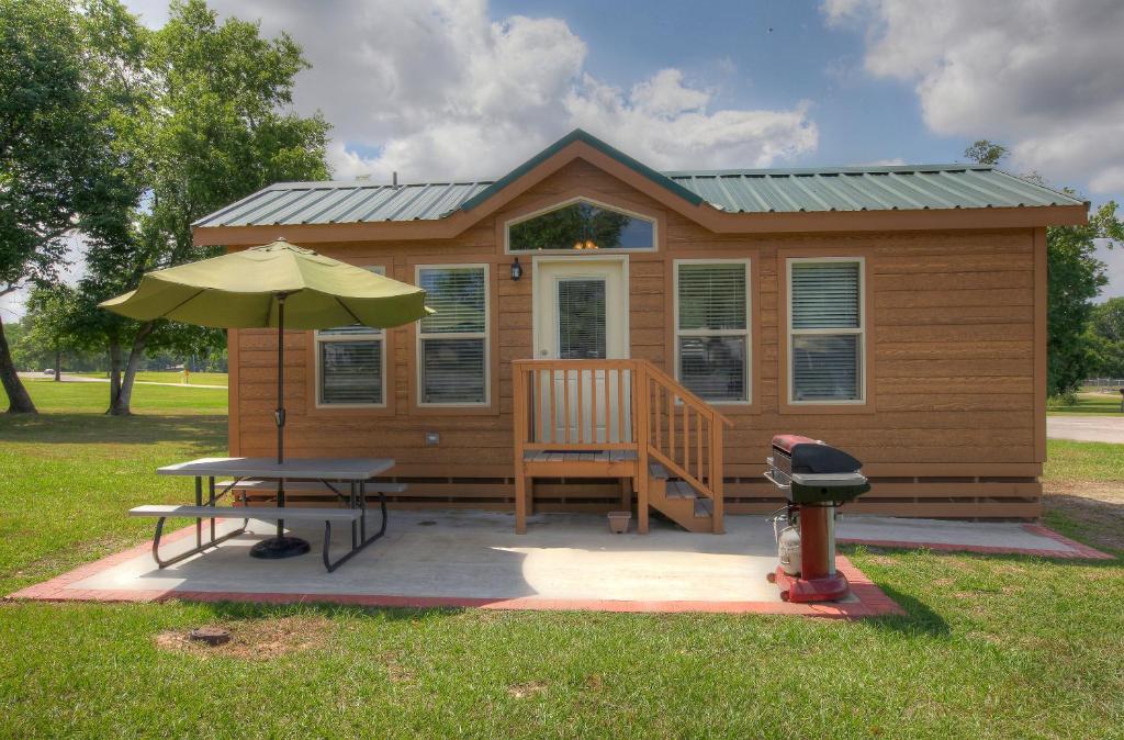 a tiny house with a table and an umbrella at Lake Conroe Two-Bedroom Cabin 13 in Willis