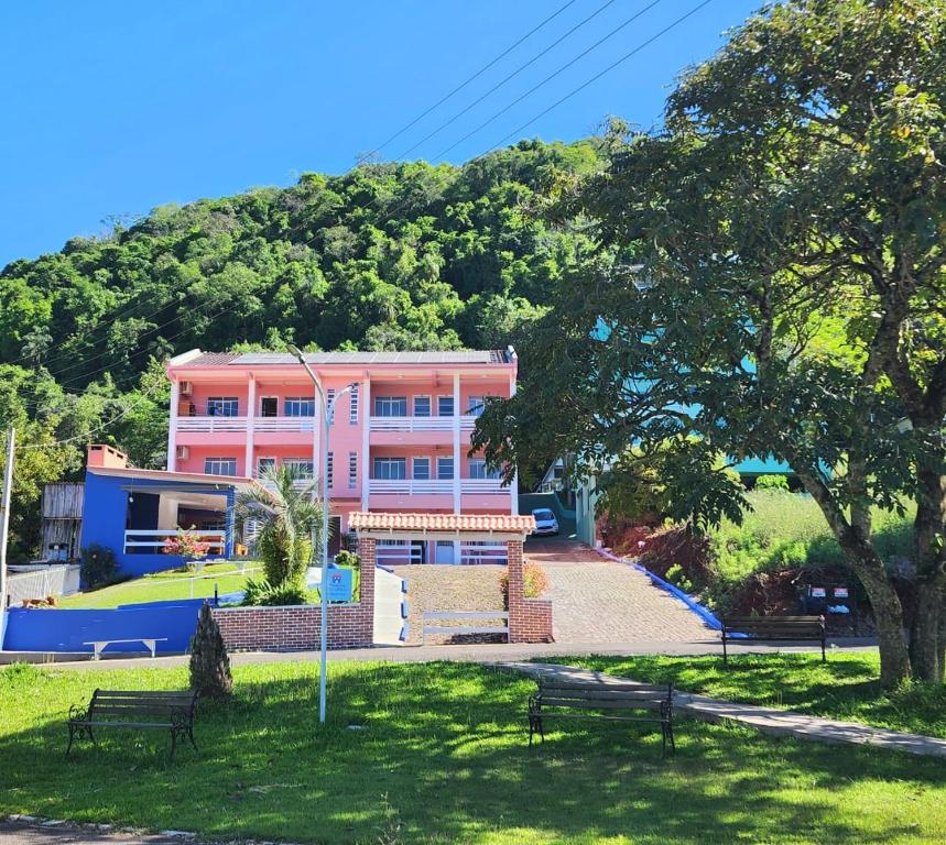 a pink building with a hill in the background at Pousada do Lago in Marcelino Ramos