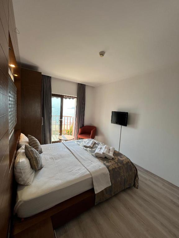 a bedroom with a bed and a chair and a window at Small Beach Hotel in Bodrum City