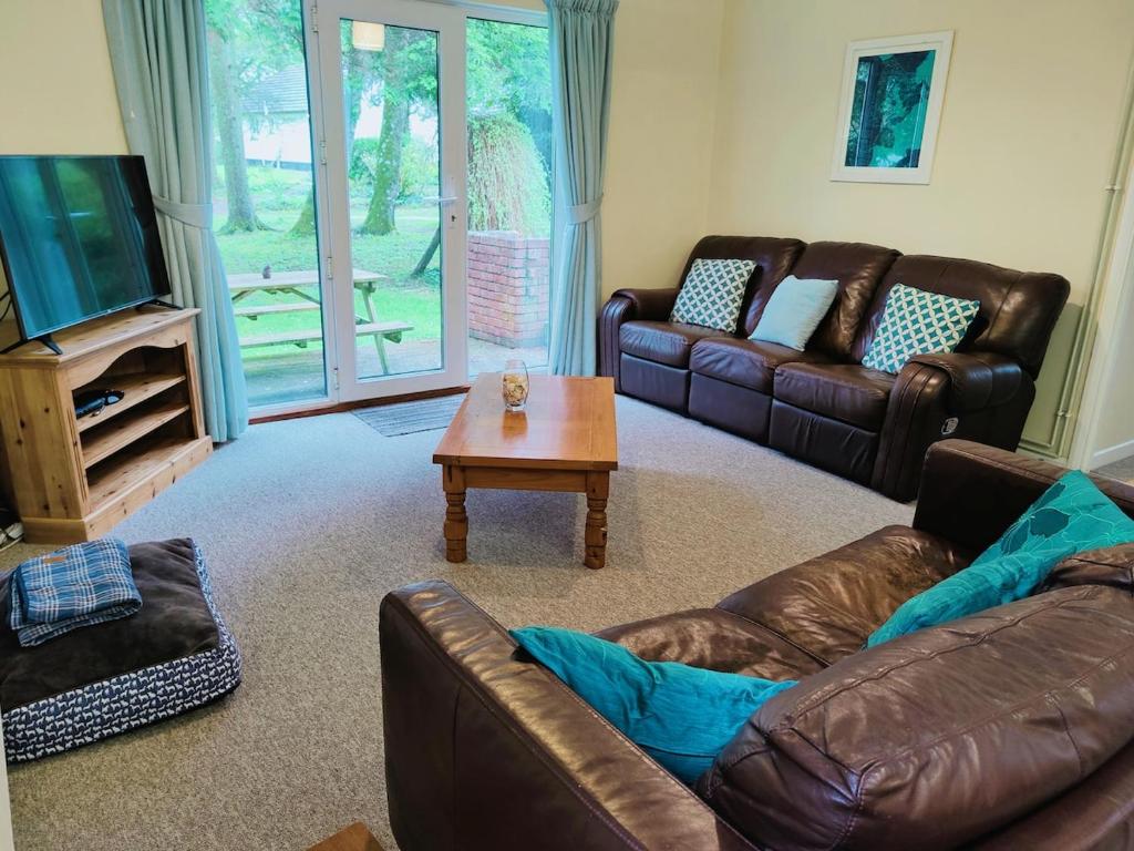 a living room with two leather couches and a coffee table at Little Croft, woodland setting sleeps 2 plus 2 kids near Perranporth in Perranzabuloe