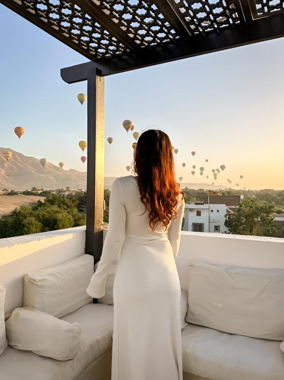 a woman in a white dress watching hot air balloons at Al Wadi Hôtel in Al Aqālitah