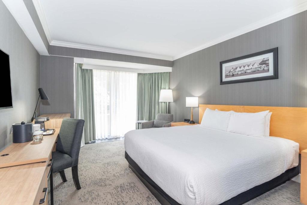 a hotel room with a large bed and a desk at Sandman Signature Vancouver Airport Hotel & Resort in Richmond