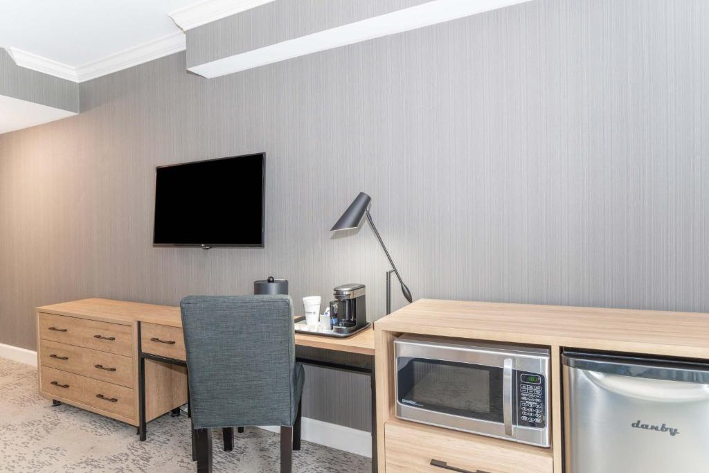 a room with a desk with a microwave and a table with a chair at Sandman Signature Vancouver Airport Hotel & Resort in Richmond