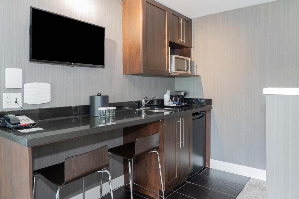 a room with a kitchen with a sink and a tv at Sandman Signature Vancouver Airport Hotel & Resort in Richmond