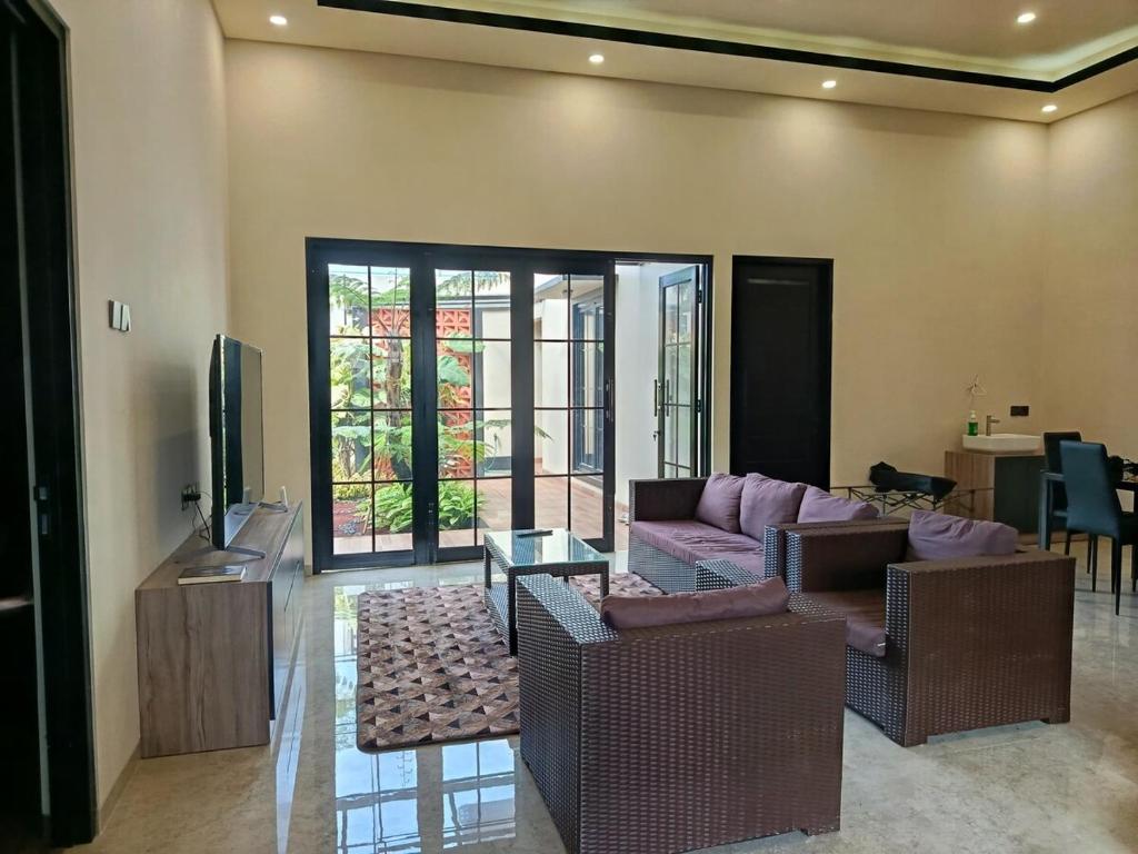 ein Wohnzimmer mit Sofa und Fernseher in der Unterkunft Villa Tasnim Syariah Landungsari in 