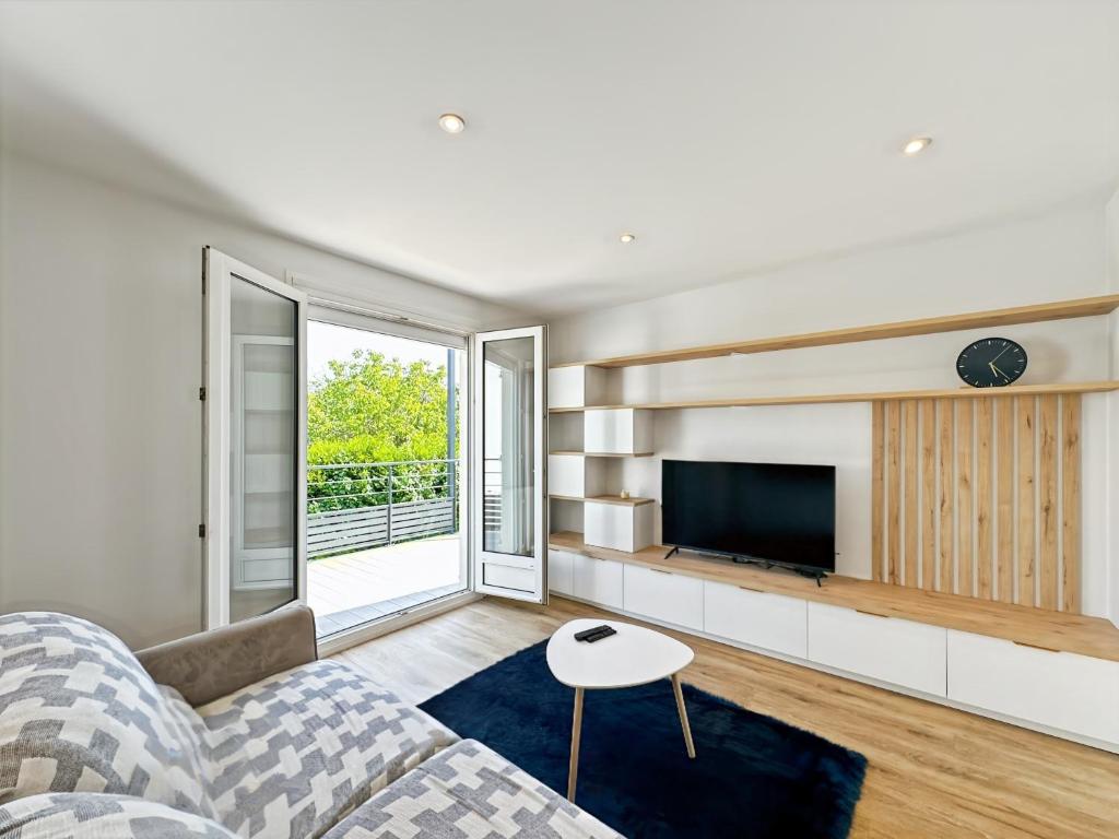 un salon avec un canapé et une télévision dans l'établissement Le Céleste - Élégance raffinée - Terrasse - Plages, à Saint-Malo