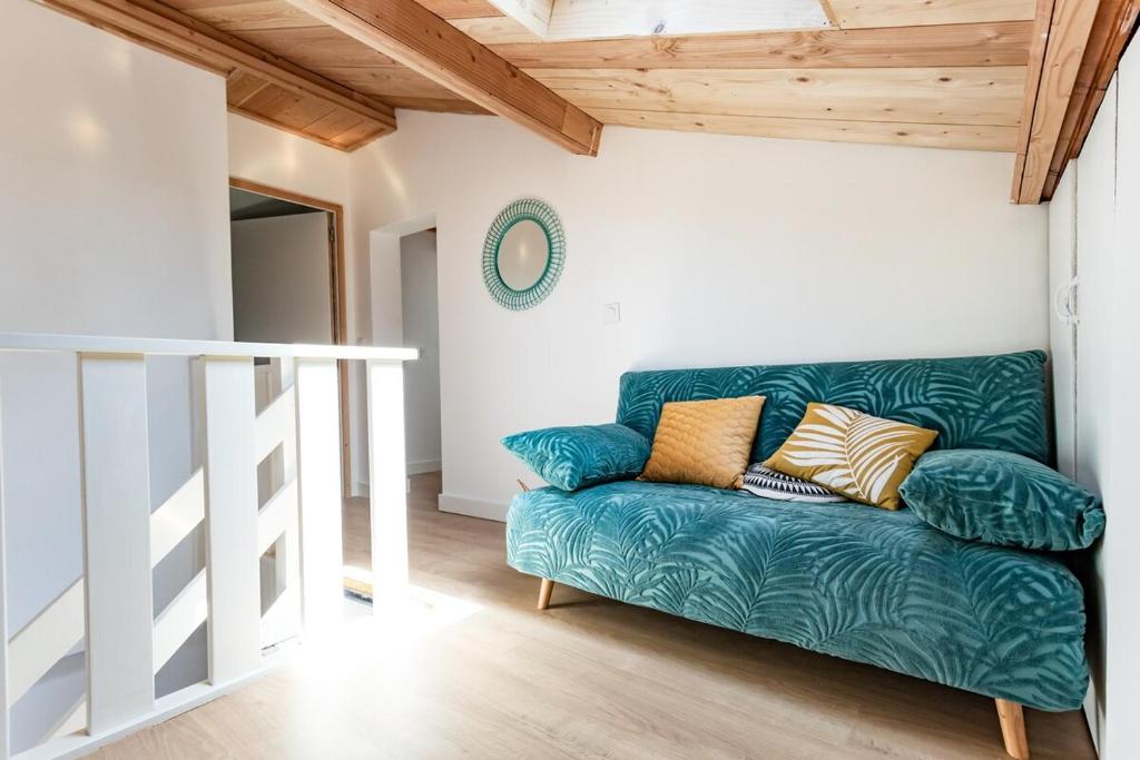 - un canapé vert dans une chambre dotée d'un plafond en bois dans l'établissement T3 bien situe a La Teste proche d Arcachon, à La Teste-de-Buch