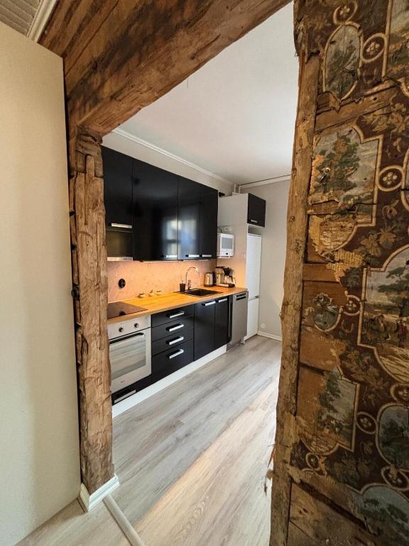 a kitchen with black cabinets and a wooden floor at Historic SELF-SERVICE apartment in downtown Vaasa in Vaasa