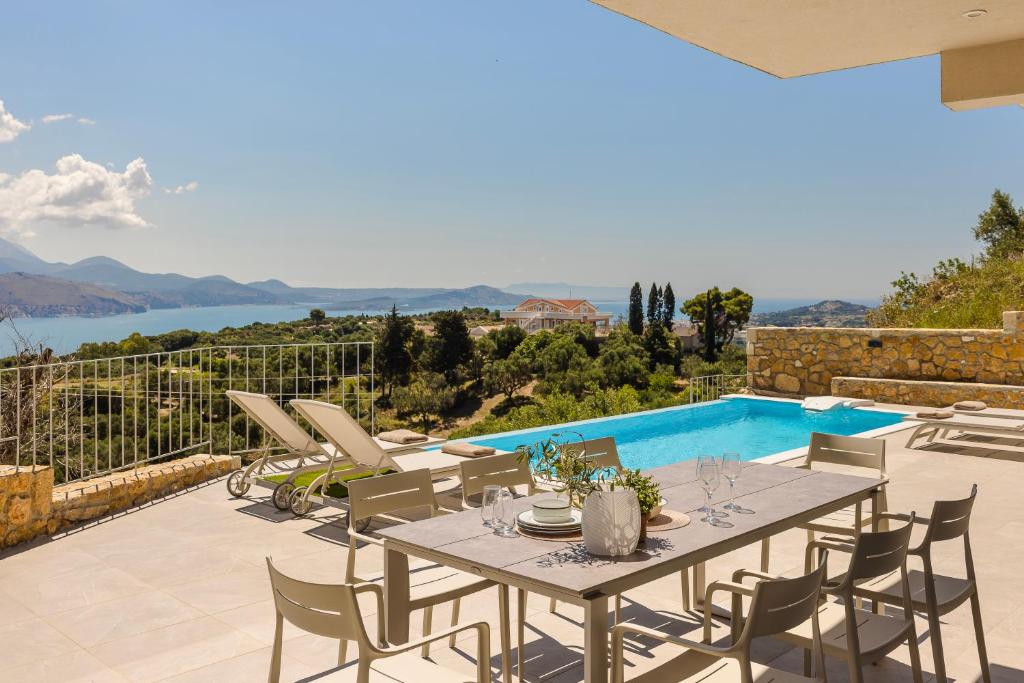 a patio with a table and chairs and a swimming pool at Arsinoe Villa in Kouvaláta