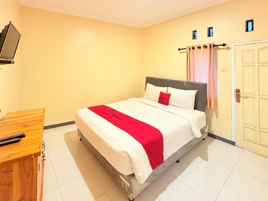 a bedroom with a bed with a red blanket at RedDoorz Syariah at Nusa Indah near BNS in Batu