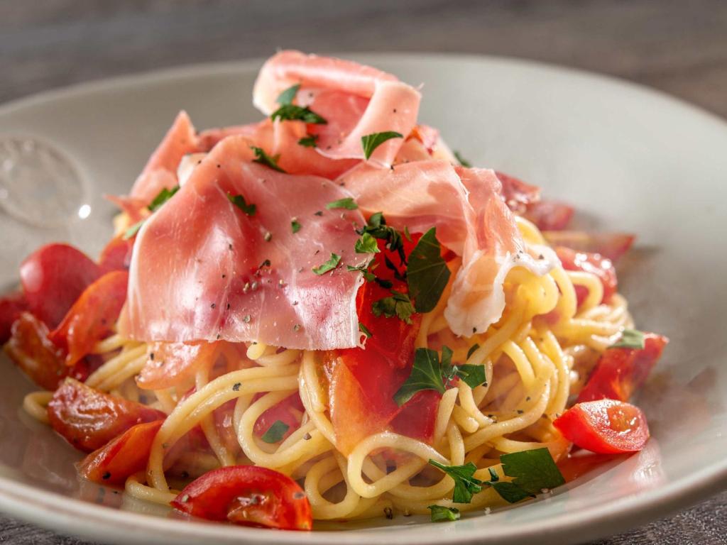 a plate of pasta with ham on top of it at Hotel Mystays Premier Akasaka in Tokyo