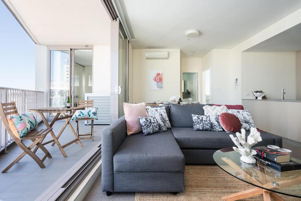 シドニーにあるTop Floor 2br Pool, Gym, Parking Airport, Cityのソファとガラスのテーブルのあるリビングルーム
