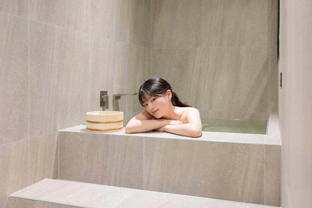 大田Aank Hotel and Spa Daejeon Yuseong的坐在浴缸里的年轻女孩