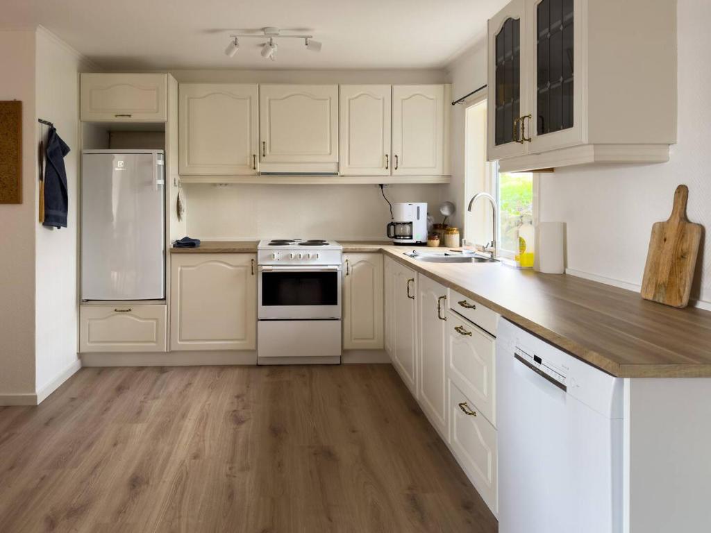 a white kitchen with white appliances and wooden floors at Central Trshavn Apartment in Tórshavn