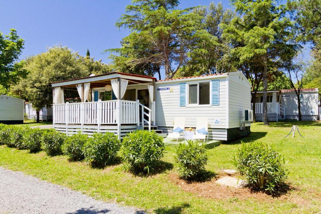 biały domek z werandą na dziedzińcu w obiekcie Quality Mobile Homes in Camping Kazela w Medulinie